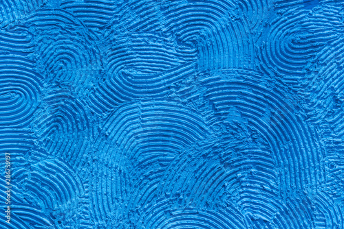 Photo of blue stucco in the form of a pattern of stripes with irregular semicircles