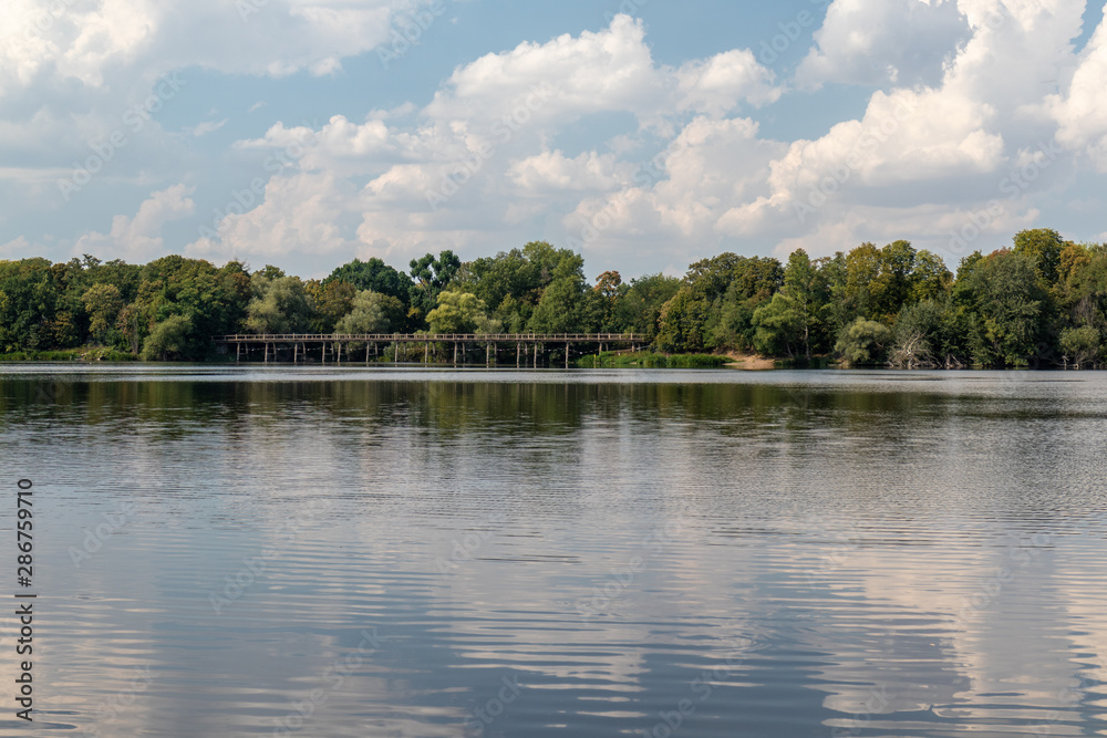 Fototapeta premium View of the popular lake Auensee in the north of Leipzig with old bridge and miniature railway