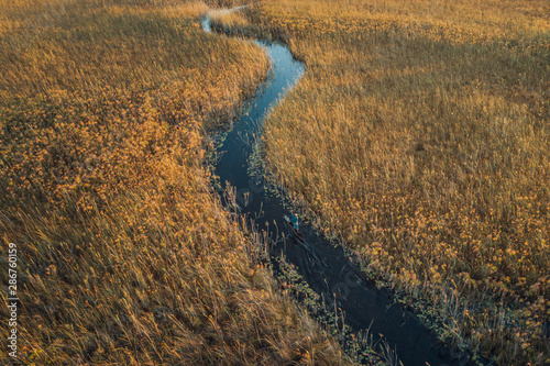 Cubango river with a man poling in a mokoro in a water channel photo