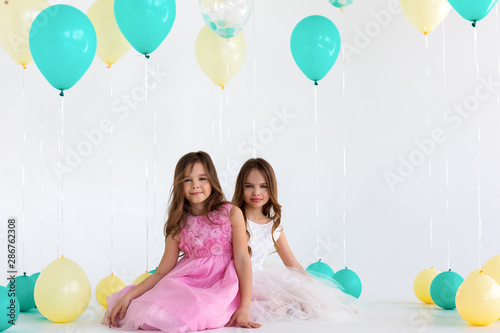Two sisters on balloons party - isolated over a white background