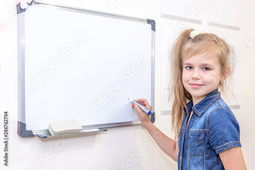 Pipil girl standing near white board. Learning and school concept photo