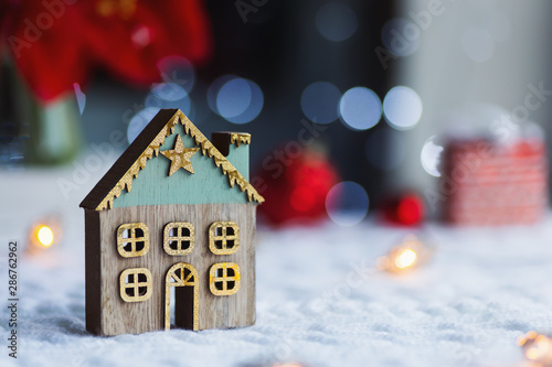 Closeup cute Christmas winter house with golden star indoor with red home festive decor and blurred bokeh background in daylight.