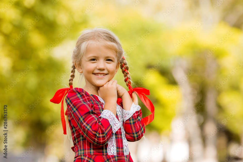 little girl blonde first grader red plaid dress smiling in the street little girl blonde first grader red plaid dress smiling in the street