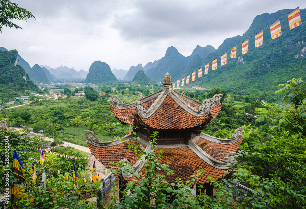 Vue aérienne sur une vallée et montagnes karstiques avec un temple au premier plan, province de Cao Bang, Vietnam.