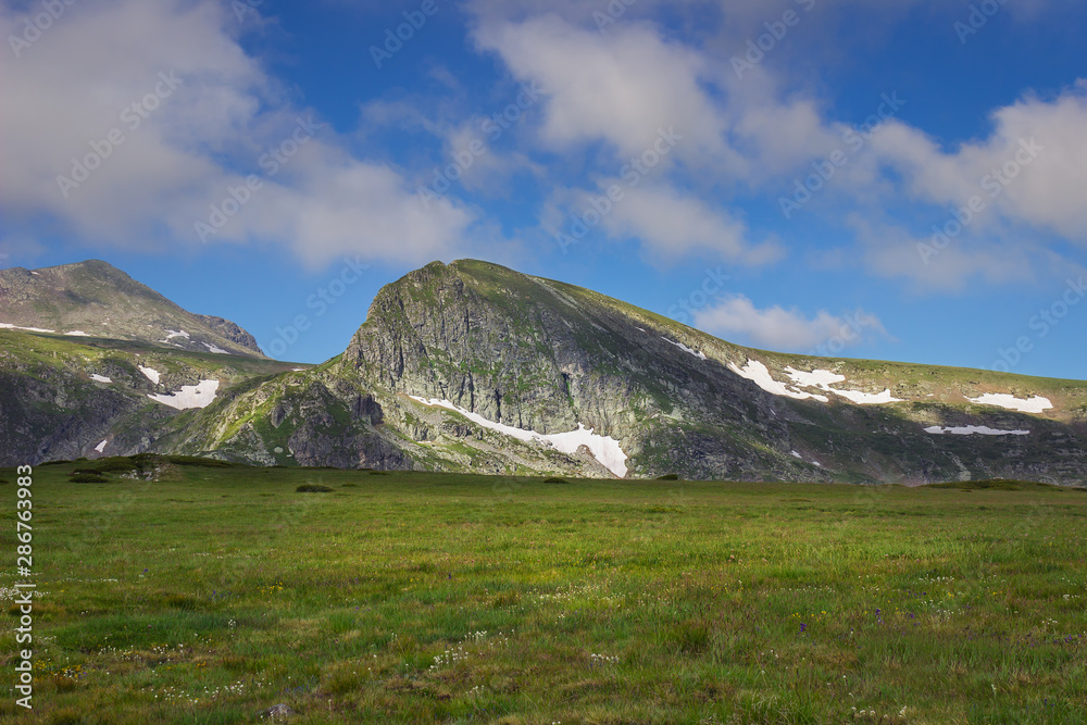Beautiful, vivid green grasslands of Rila mountain and epic rocky peaks on the tour of seven Rila lakes