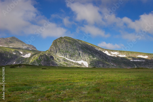 Beautiful, vivid green grasslands of Rila mountain and epic rocky peaks on the tour of seven Rila lakes