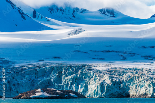 The end of a glacier in the Arctic Circle where it falls into the Arctic Ocean in Hornsund, Svalbard, Norway. photo