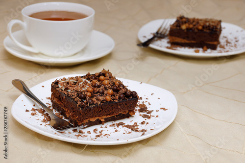 Chocolate cake and tea. Two pieces of sponge cake on a white plate and a white cup with tea