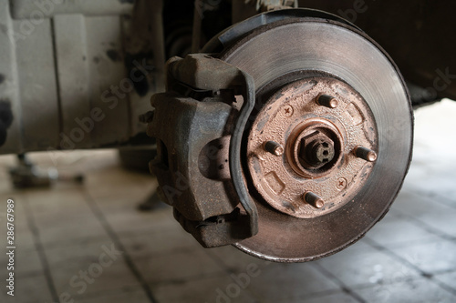 Old worn brake discs on a passenger car. Car on a lift in a car service.