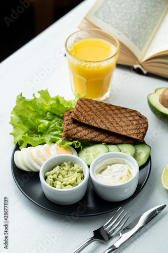 Crunchy rye toasts with fresh lettuce  hard boiled eggs  cream cheese  guacamole and cucumber with fresh pulpy orange juice - a perfect combo for slow breakfast