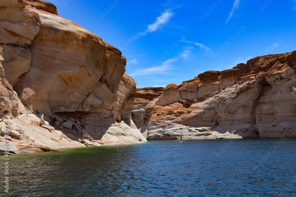 Lake Powell's beautiful rock formations lead right to the water against a blue sky