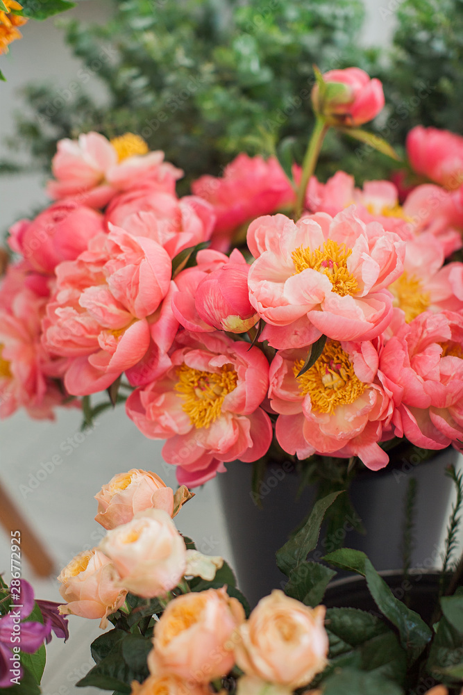 Coral peonies in a glass vase on a table. Beautiful peony flower for floral shop concept. Fresh cut bouquet. Flowers delivery. Copy space