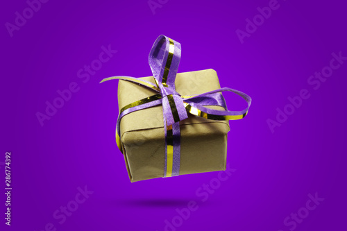 hristmas gift boxes wrapped in craft paper with purple ribbon on purple background