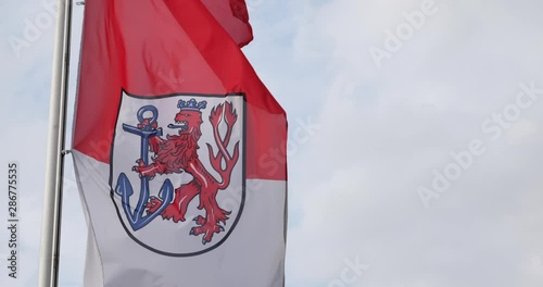 Flag of the city of Düsseldorf in the state of North Rhine-Westphalia, Germany waving in wind and background of cloudy sky.