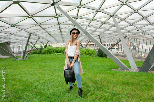 Elegant beautiful blonde woman walks on the street of hight modern city. European white woman tourist outdoor in asian city. Summer vacation. Happy young woman see the sights.