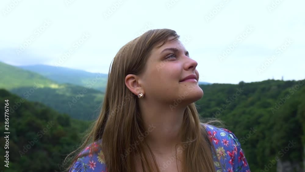Young Woman smiles. Tourist Travel Vacation. Traveling mountains, freedom and active lifestyle concept. Young girl traveler at cityscape beautiful view background in Okatse canyon, Georgia. Slow mo Young Woman smiles. Tourist Travel Vacation. Traveling mountains, freedom and active lifestyle concept. Young girl traveler at cityscape beautiful view background in Okatse canyon, Georgia. Slow mo