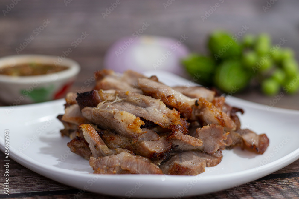 Charcoal-boiled pork neck and sauce on a wooden background .Grilled Pork thai food