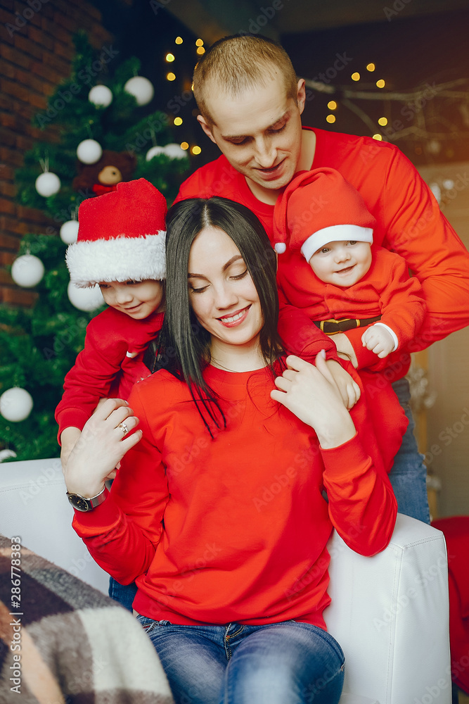 Cute family have fun in decorating room. Beautiful mother with little children and husband. Family in a red sweaters