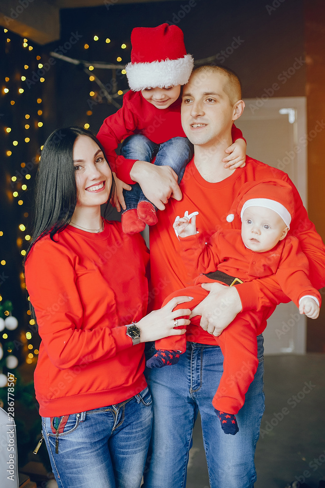 Fototapeta premium Cute family have fun in decorating room. Beautiful mother with little children and husband. Family in a red sweaters