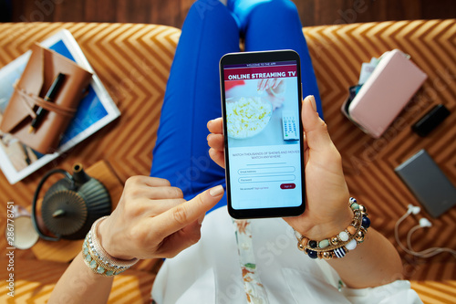 Canvas Print modern housewife subscribing to internet tv on smartphone