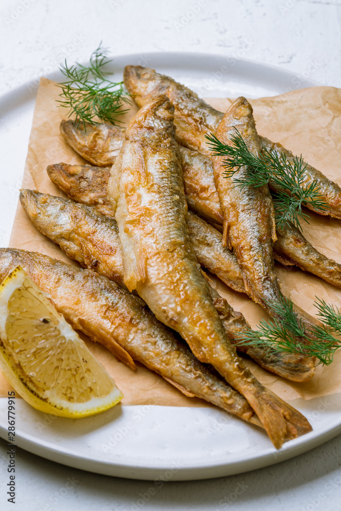 fried surmullet on white plate on white concrete table fried surmullet on white plate on white concrete table