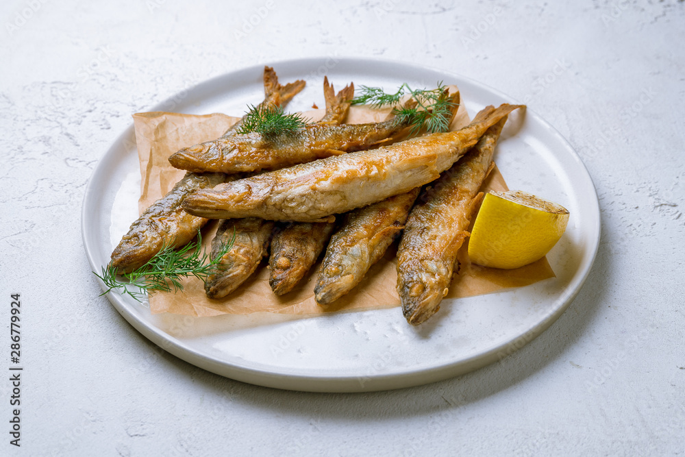 fried surmullet on white plate on white concrete table fried surmullet on white plate on white concrete table