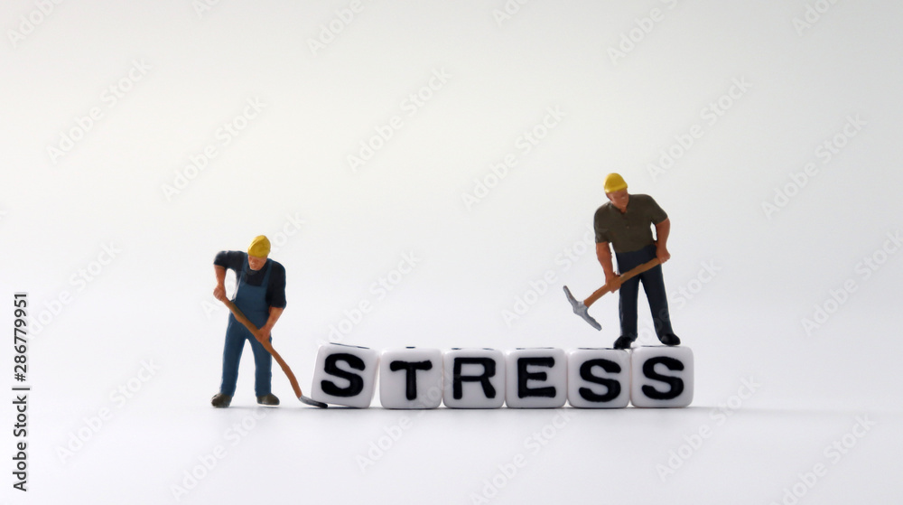 The word STRESS on white cubes with miniature people.