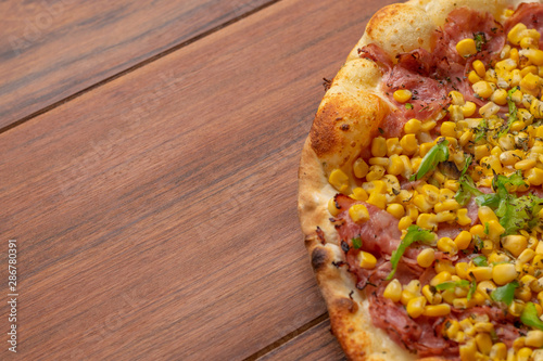 Pepperoni and corn pizza on a wooden background. Top view. Flat view.