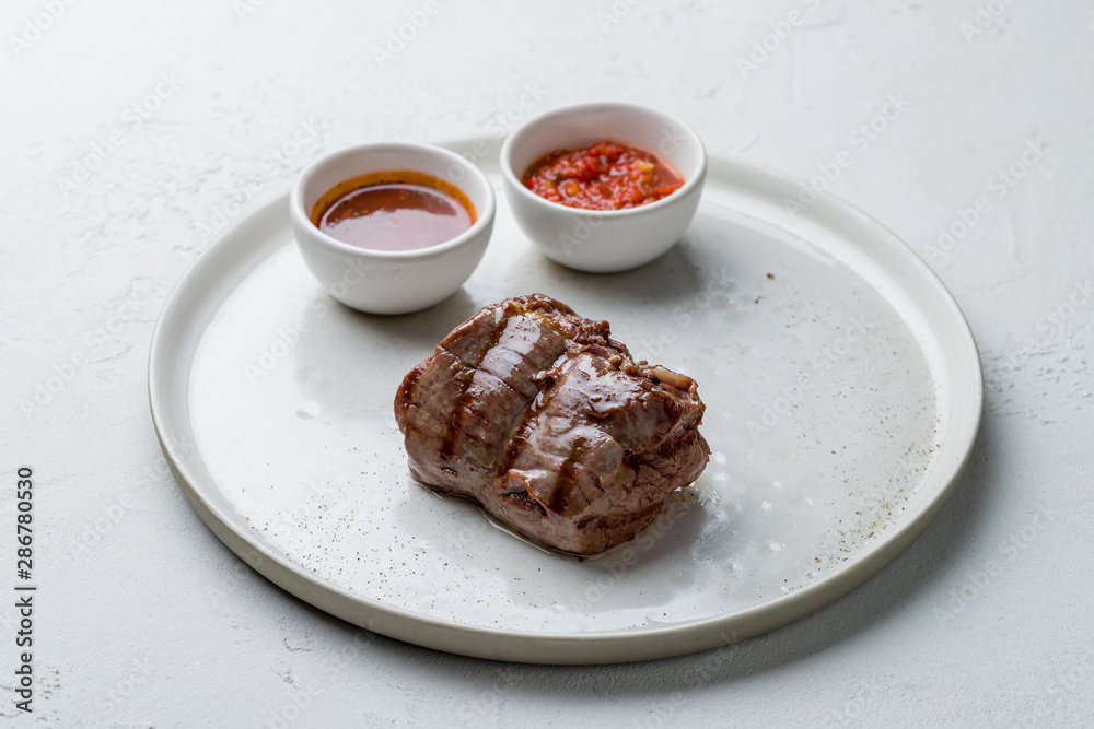 grilled steak filet Mignon with sauses on white concrete table grilled steak filet Mignon with sauses on white concrete table