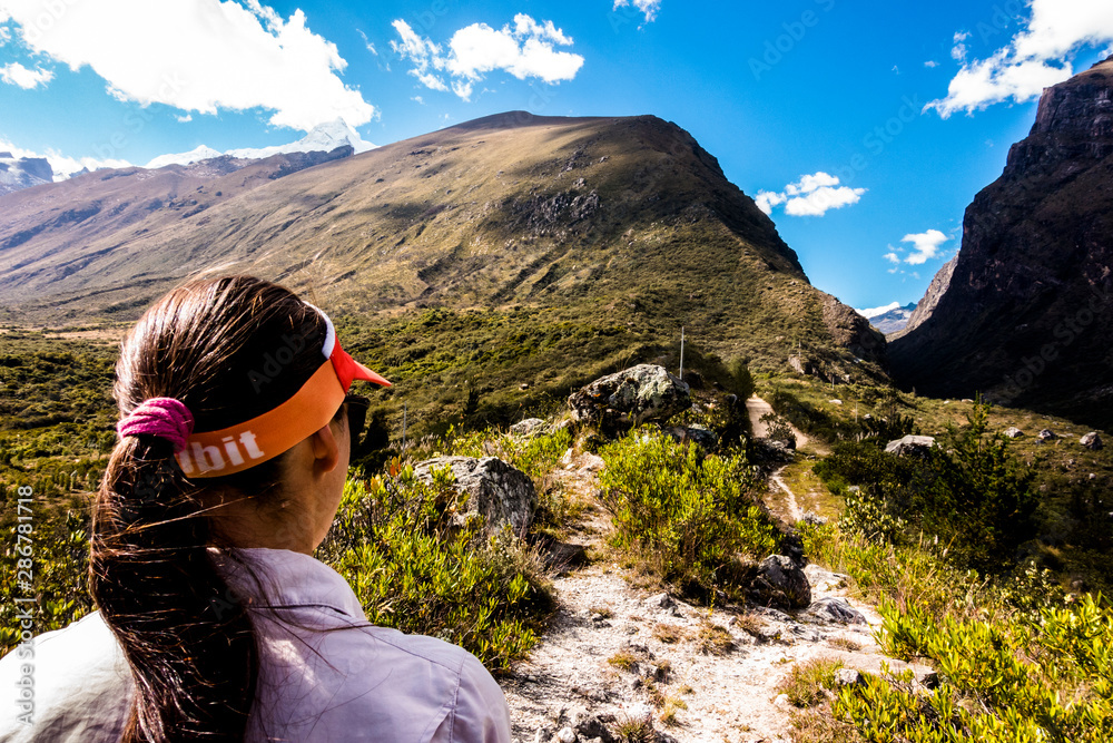 Female runner looking at the upcoming mountain trail in the Cordillera Blanca mountain range in Peru.  