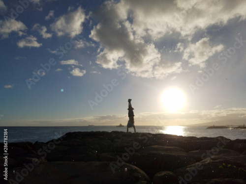 Man Handstand on Rocks along the water at sunset