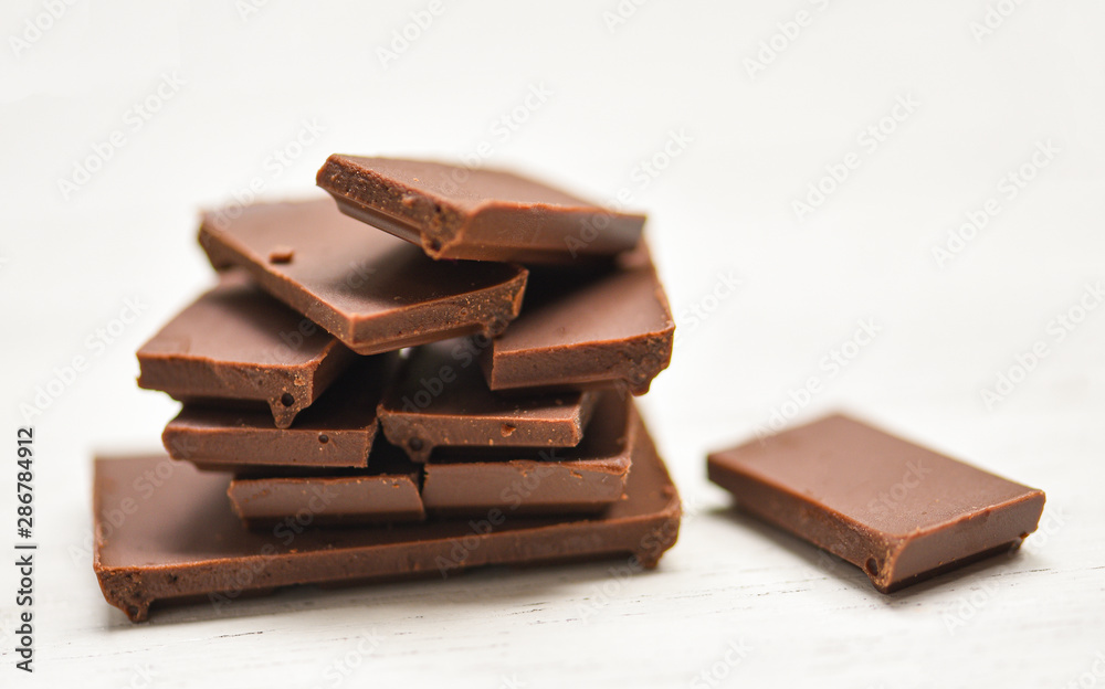 chocolate bar stacked on the white wood background - close up Chocolate pieces candy sweet dessert and snack , selective focus chocolate bar stacked on the white wood background - close up Chocolate pieces candy sweet dessert and snack , selective focus