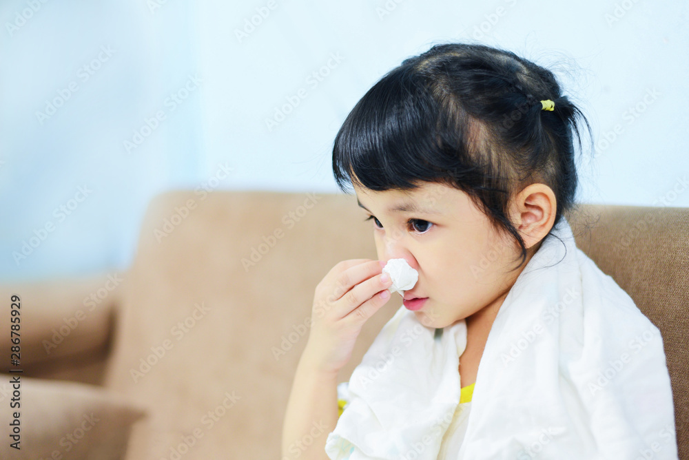 Asian little girl sick wrapped in handkerchief get cold and blow nose the flu season child runny nose and sneezing blowing their nose and fevers at home Asian little girl sick wrapped in handkerchief get cold and blow nose the flu season child runny nose and sneezing blowing their nose and fevers at home