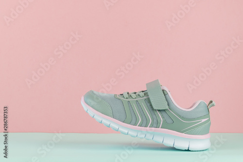 Walking sneaker with left foot on blue and pink background.