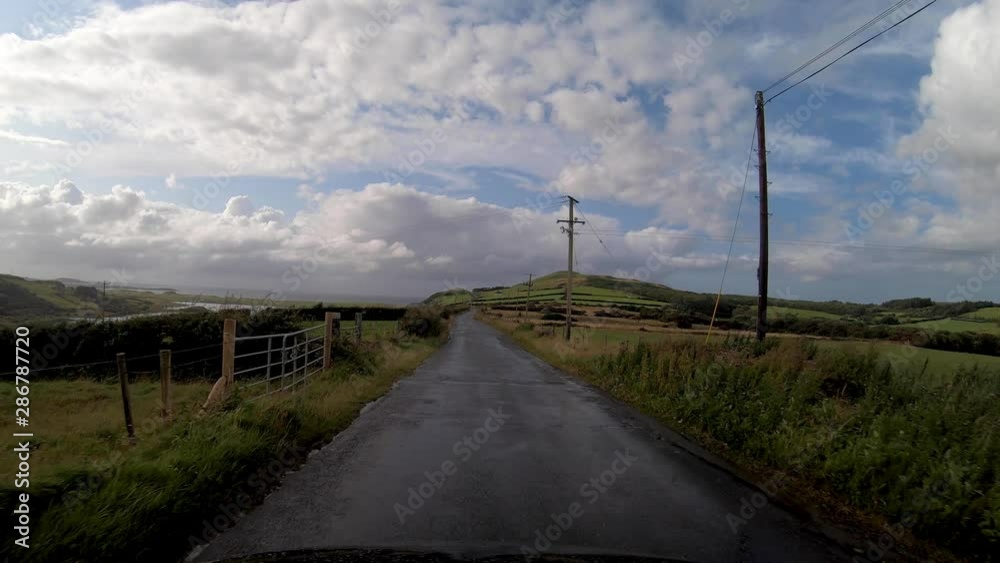 Wide Driving Shot of Stunning Irish Fields and Hillside on Single Track with Blue Skies after Rain Wide Driving Shot of Stunning Irish Fields and Hillside on Single Track with Blue Skies after Rain