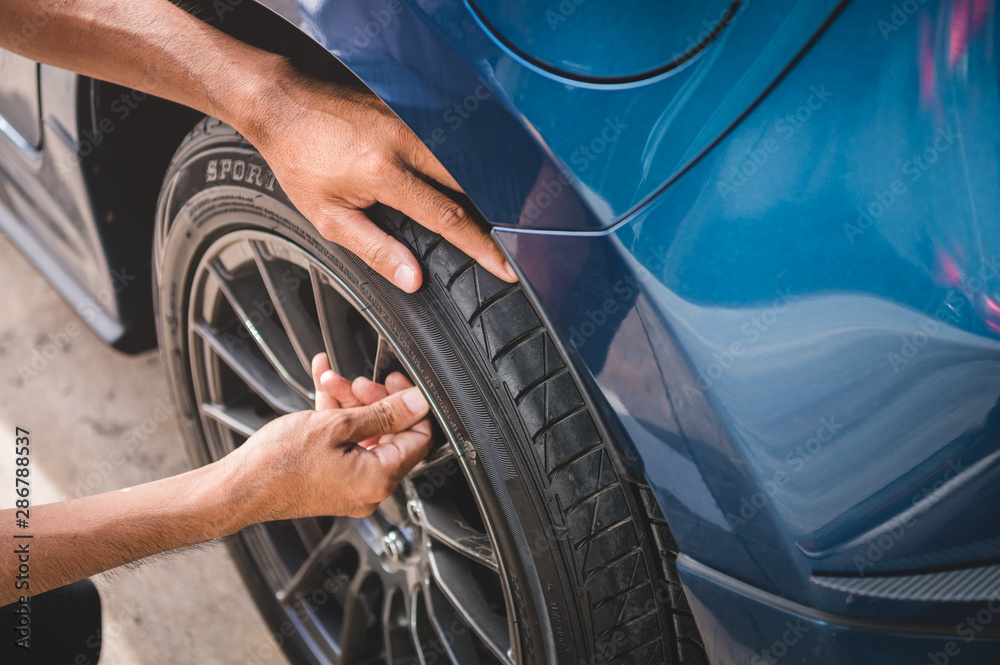 Closeup male automotive technician removing tire valve nitrogen cap for tire inflation service at garage or gas station. Car annual maintenance and repair concept. Safety road trip and travel theme. Closeup male automotive technician removing tire valve nitrogen cap for tire inflation service at garage or gas station. Car annual maintenance and repair concept. Safety road trip and travel theme.