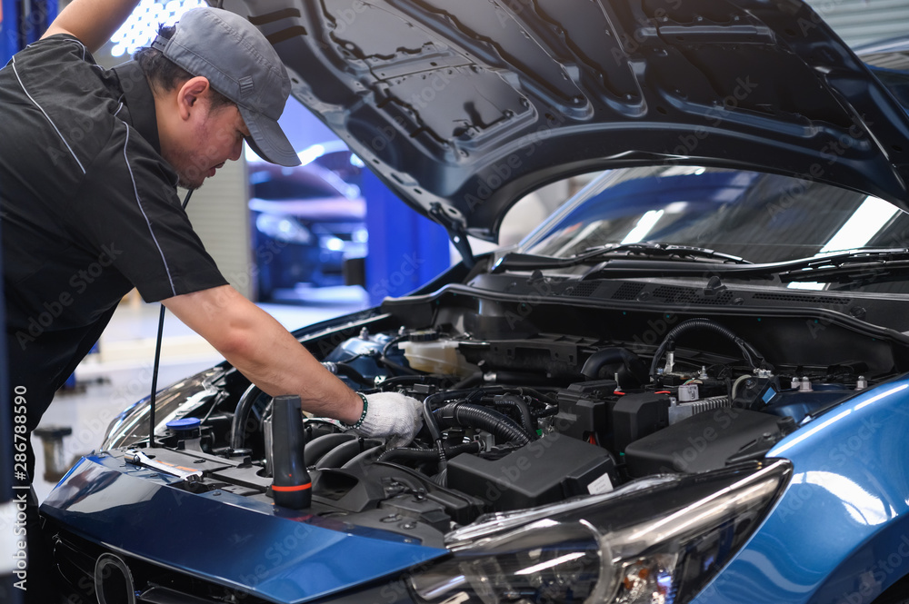 Asian male auto mechanic examine car engine breakdown problem in front of automotive vehicle car hood. Safety technical inspection care check service maintenance for customer before long road trip