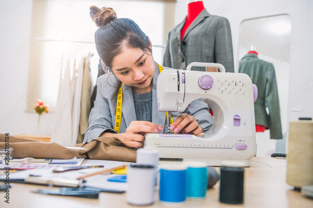 Attractive female fashion designer hand working in workshop with sewing  machine. Stylish fashionista woman creating new cloth design collection.  Tailoring and sewing Lifestyle and business occupation Stock Photo | Adobe  Stock