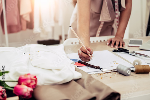 Closeup of attractive female fashion designer hand working in home office workshop. Stylish fashionista woman creating new cloth design collection. Tailoring and sewing People lifestyle and occupation