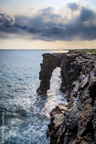 Dramatic clouds over the Holei Sea Arch in Hawaii photo