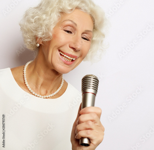 Papier peint singes - Papier peint lifestyle and people concept: Portrait of charming modern grandmother holds up the microphone stand and sings