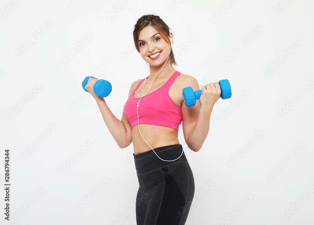 Picture of fit and healthy young woman smiling and holding dumbbelsl to shoulder. Sport and people concept. Picture of fit and healthy young woman smiling and holding dumbbelsl to shoulder. Sport and people concept.