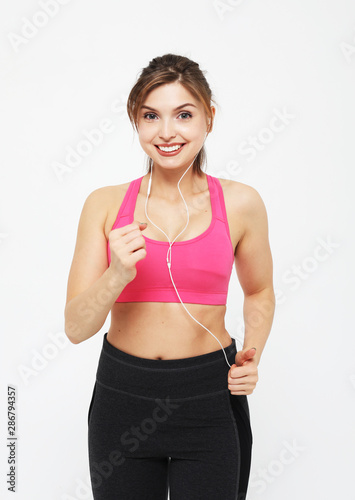 portrait of a smiling fitness woman in headphones working out isolated over white background © Raisa Kanareva