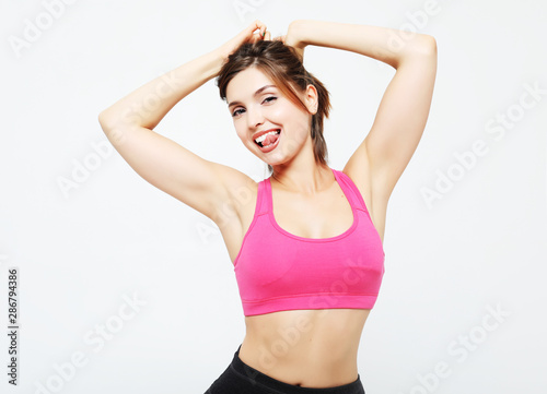 portrait of a smiling fitness woman in headphones working out isolated over white background