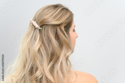 A large photo portrait of a pretty model with long hair and a beautiful hairstyle on a white background. Back view.