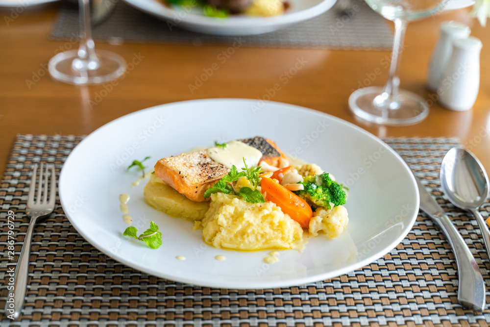 Fresh romantic breakfast table next to morning briliant light window, with salmon fish, mashed potato, vegetable, red wine Fresh romantic breakfast table next to morning briliant light window, with salmon fish, mashed potato, vegetable, red wine