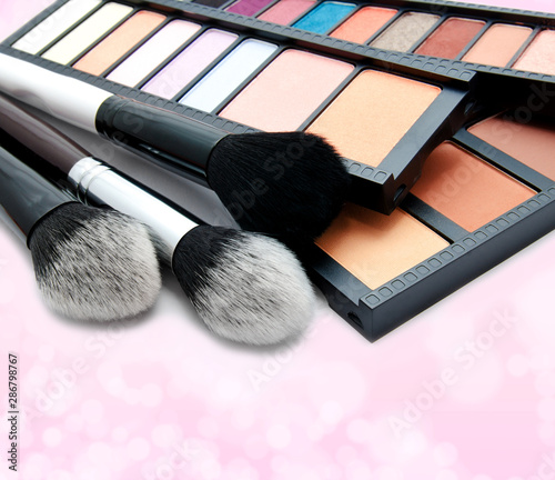 Various set of professional makeup brushes and palette of colourful eye shadows