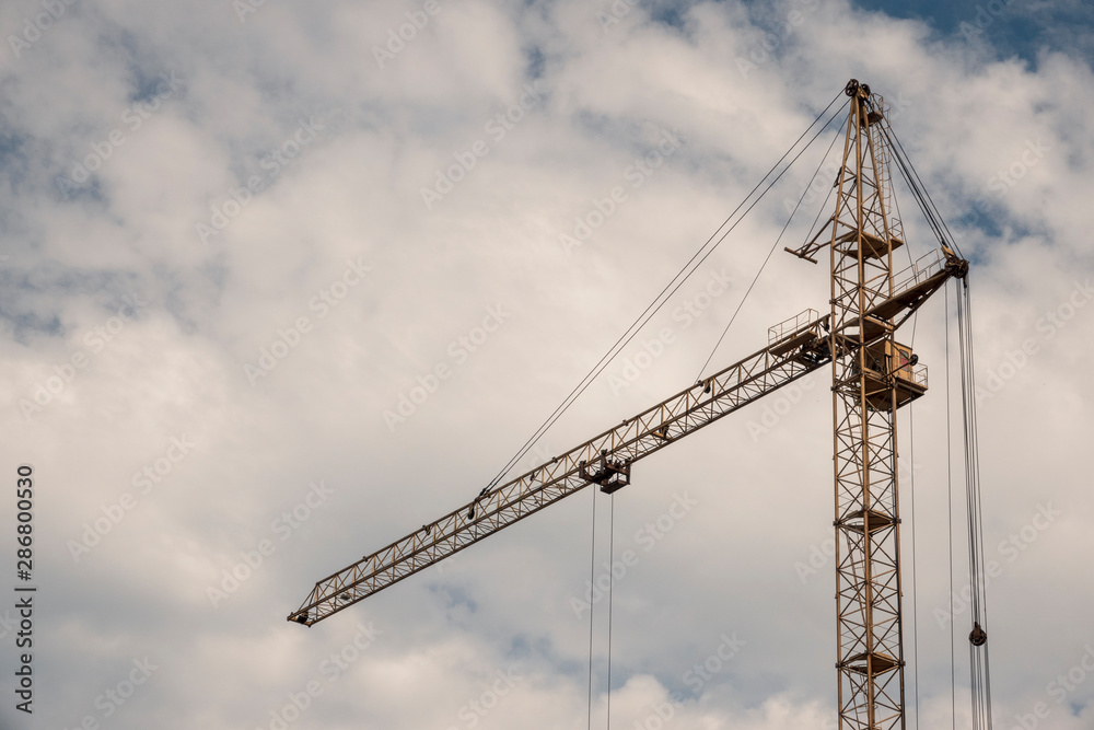 High-rise construction crane on a background of clouds.