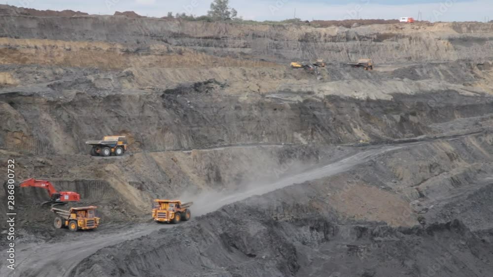 Panorama open pit coal mining. Yellow dump trucks drive with coal Panorama open pit coal mining. Yellow dump trucks drive with coal