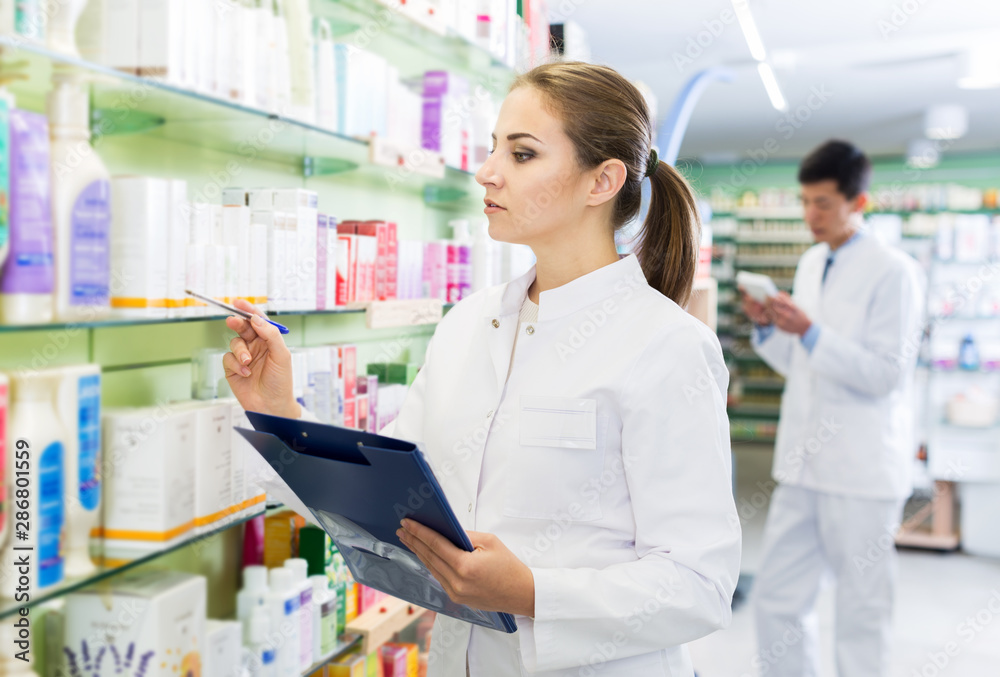 Female pharmacist stocktaking medicines